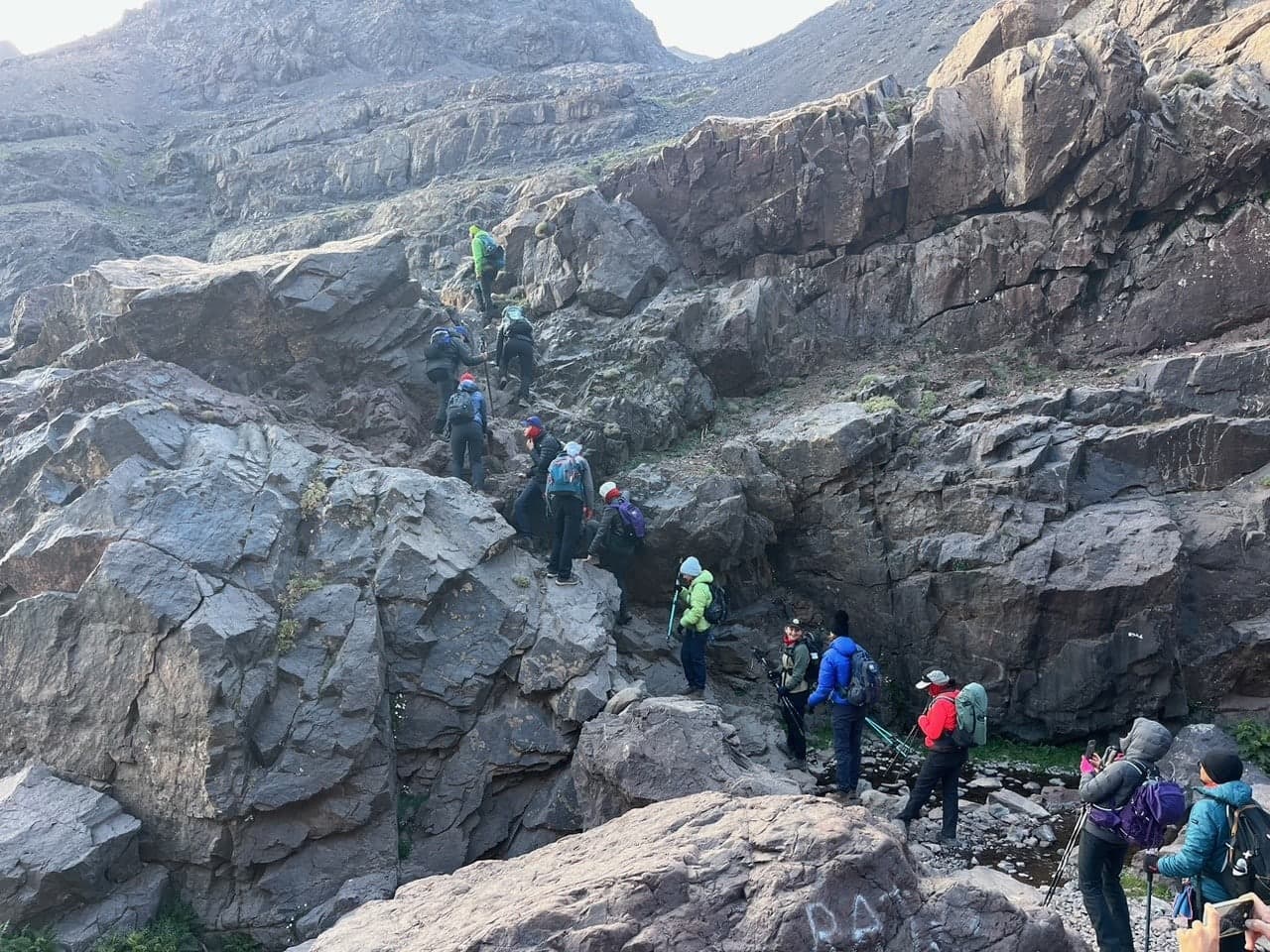 A group of trekkers picking their way up a rocky section of the Toubkal trail